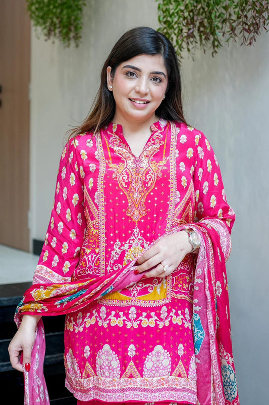 Smiling woman wearing vibrant pink ethnic wear with intricate floral patterns and holding matching dupatta indoors