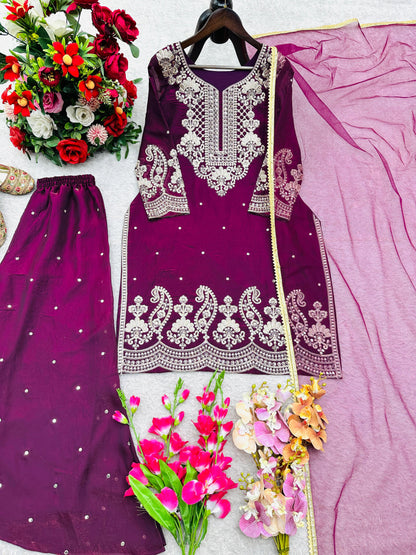 Purple ethnic women's suit with intricate silver embroidery, matching dupatta, and pants displayed with floral decorations