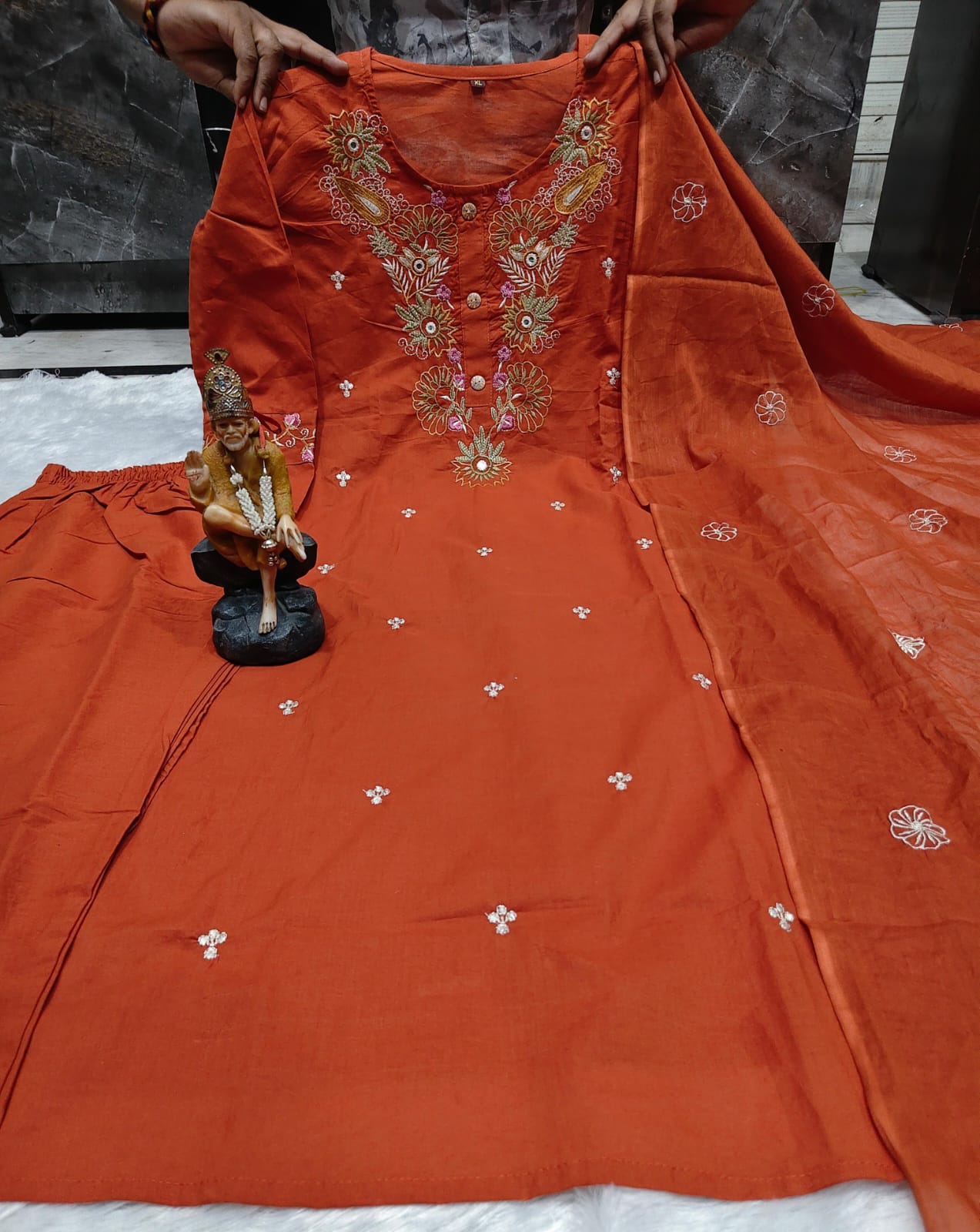 Close up view of traditional artisan embroidery work and high quality thread detailing on a rich rust orange super dying cotton fabric bodice.
