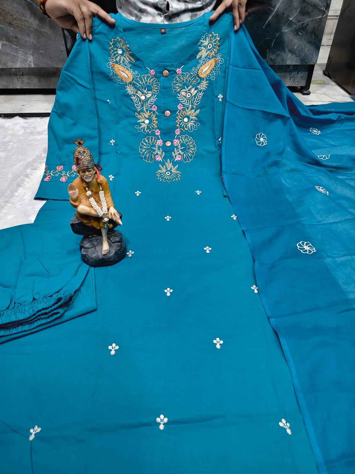Close up view of traditional artisan embroidery work and high quality thread detailing on a rich teal blue super dying cotton fabric bodice.