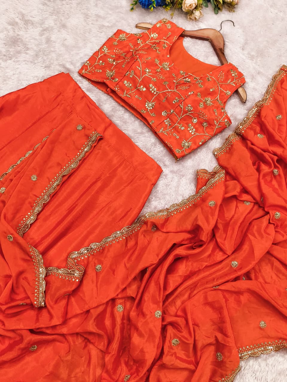 Side perspective highlighting the pre draped orange chinnon silk dupatta flowing gracefully over the pleated ethnic skirt bottom.