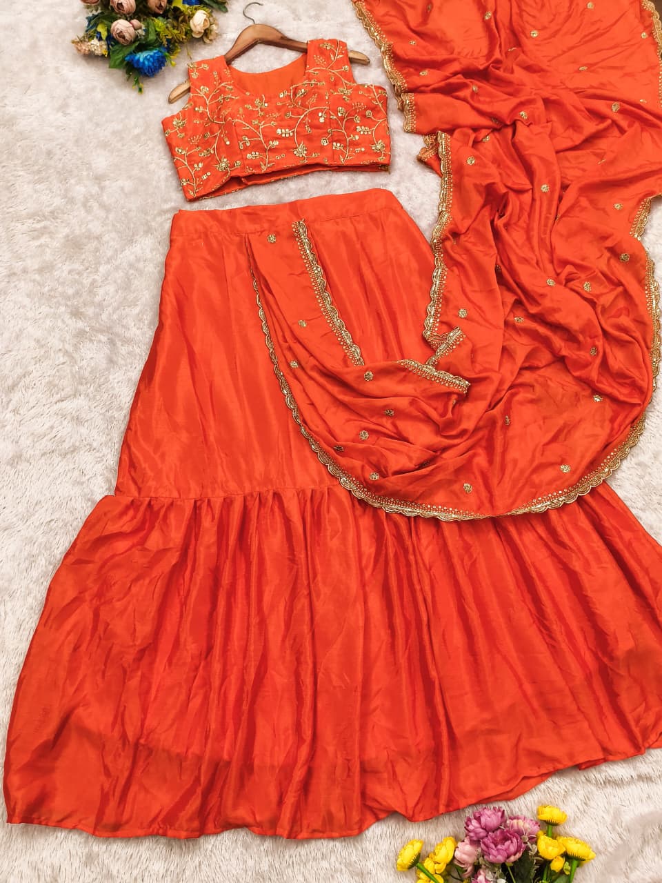 Close up view of detailed multi thread embroidery patterns and glittering sequence work on a vibrant orange chinnon silk bodice.