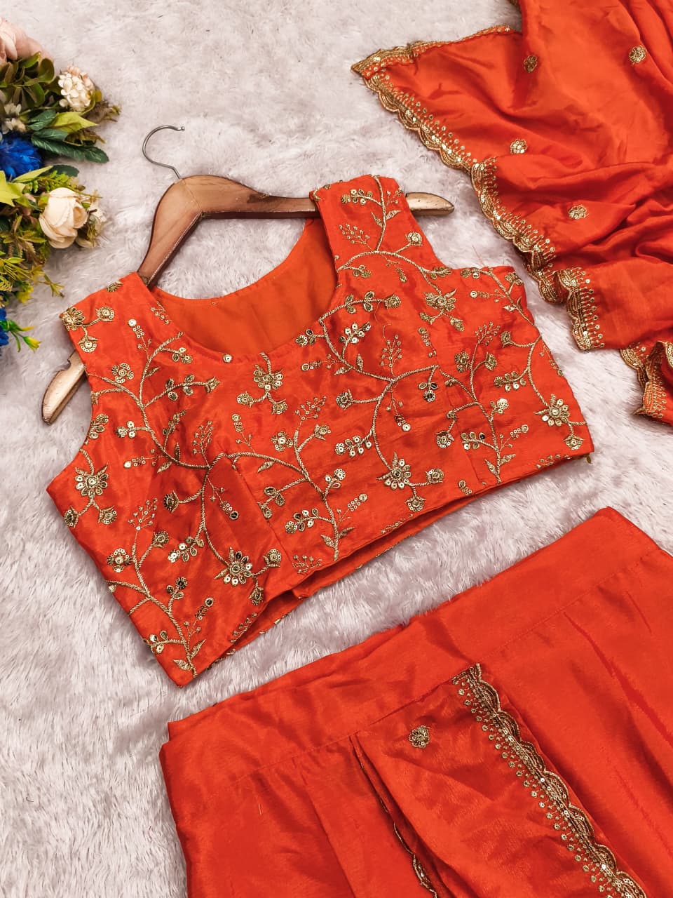 Detailed shot of the finished skirt borders displaying intricate traditional embroidery thread work on a rich orange canvas.
