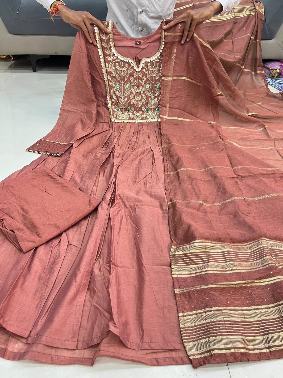 Close up view of detailed traditional embroidery work and intricate needlework patterns on a soft rosy brown chanderi fabric yoke.
