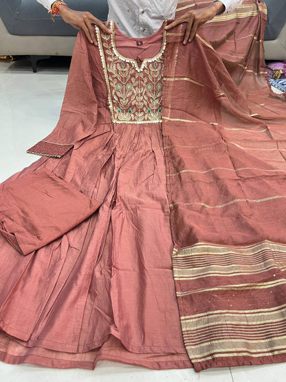 Close up view of detailed traditional embroidery work and intricate needlework patterns on a soft rosy brown chanderi fabric yoke.