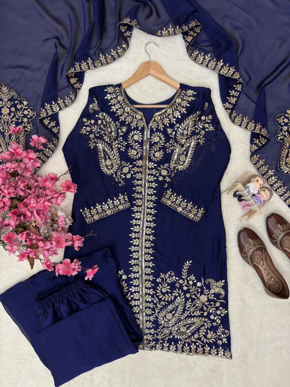 Close up view of detailed five millimeter shimmering sequins and golden zari thread embroidery work on deep navy blue silk fabric.