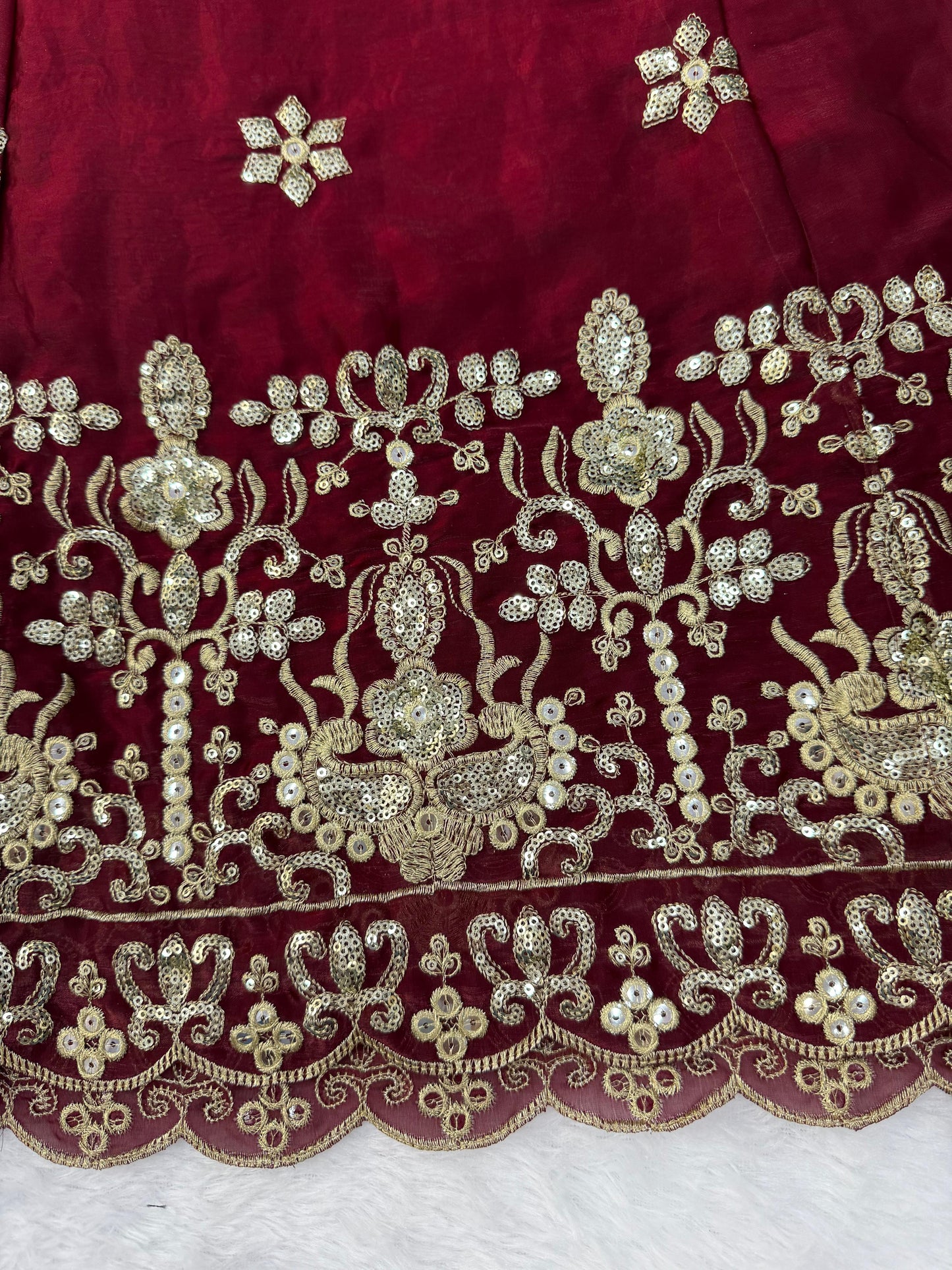 Side perspective highlighting the large three point forty meter flowing flair and regal silhouette of a maroon traditional celebratory dress.