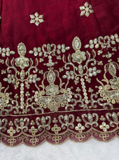 Side perspective highlighting the large three point forty meter flowing flair and regal silhouette of a maroon traditional celebratory dress.