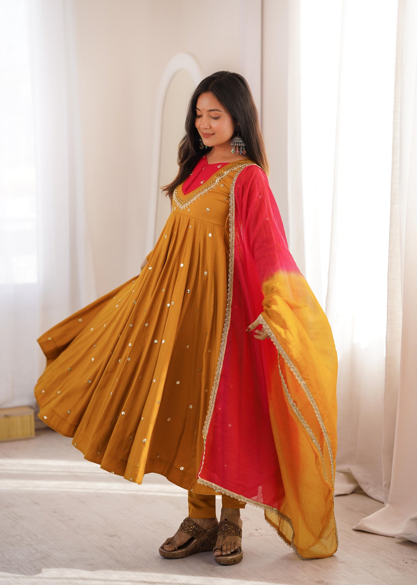 Close up view of detailed sequence embroidery work and sparkling real mirror embellishments on a bright mustard yellow roman silk fabric.