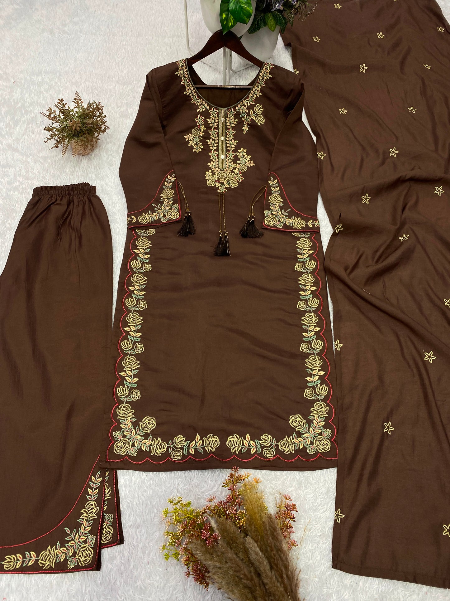 Focused shot of beautiful artisan embroidery patterns and decorative accents on deep chocolate brown roman silk material.
