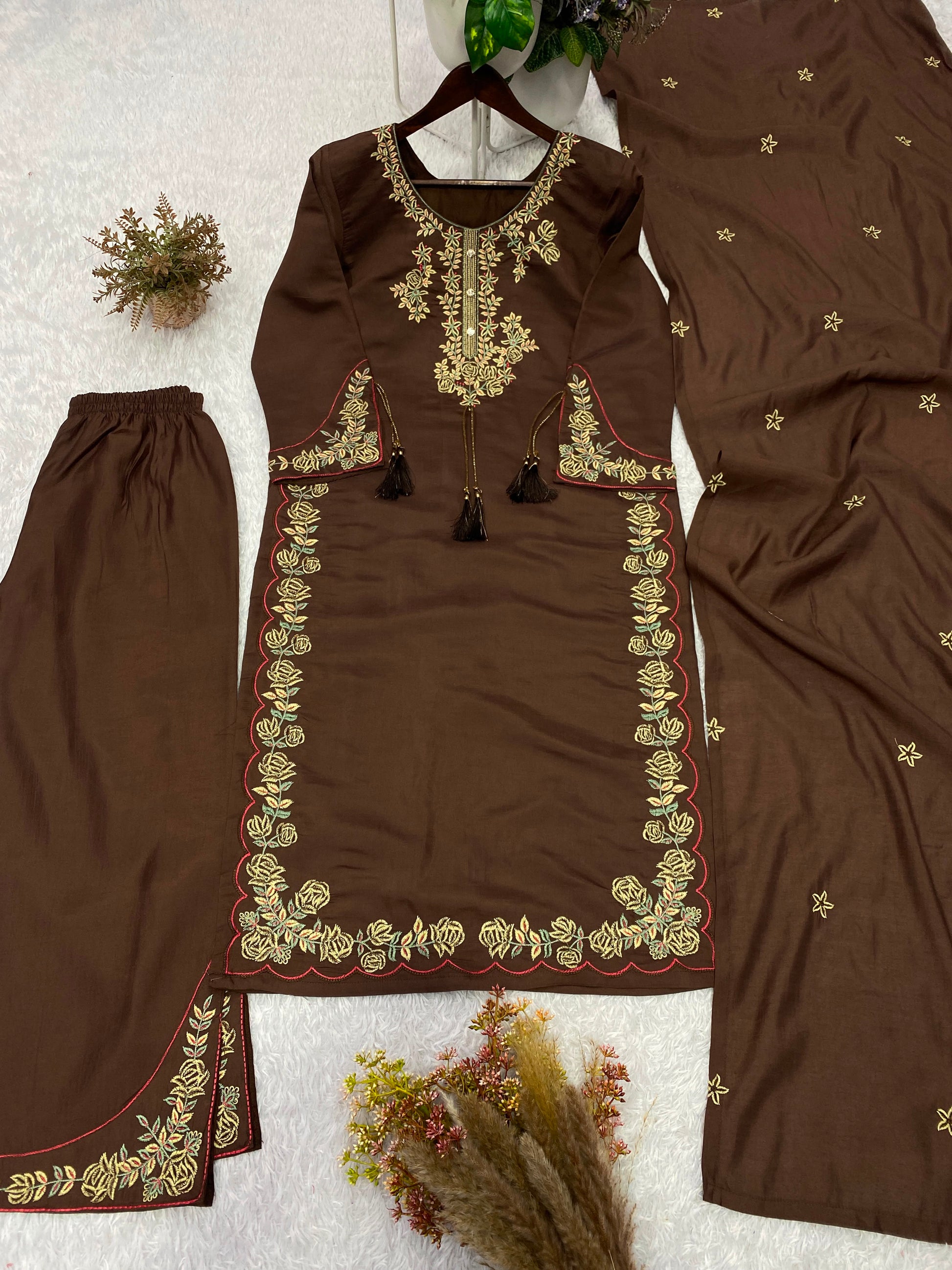 Focused shot of beautiful artisan embroidery patterns and decorative accents on deep chocolate brown roman silk material.