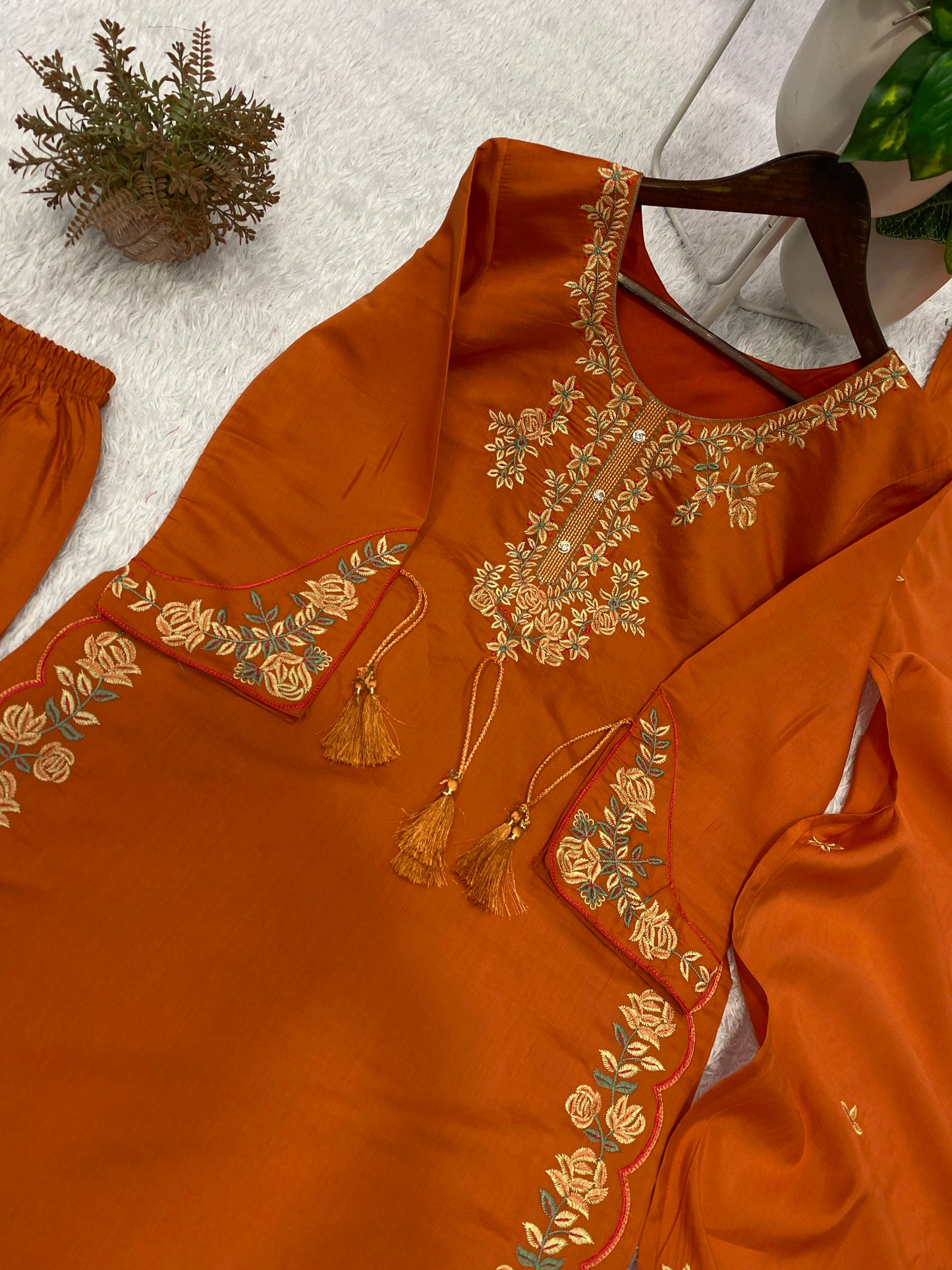 Detailed flat layout presentation of the rust orange designer outfit showing the top trousers and embroidered matching dupatta.