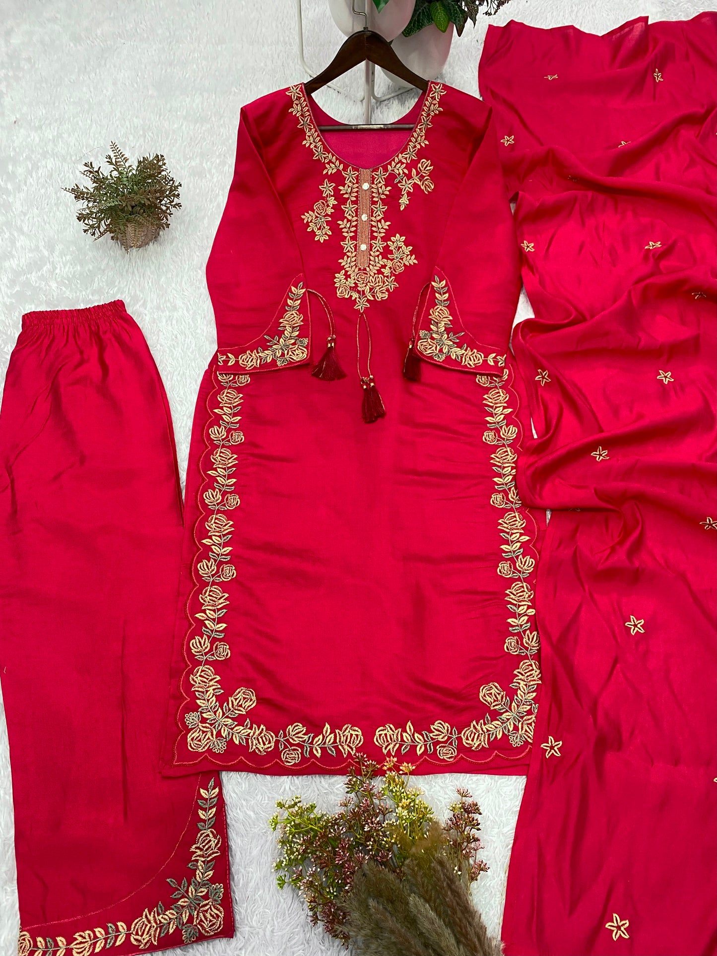 Detailed close view of shimmering embroidery needlework and traditional latkan decorations on a deep maroon red top bodice.