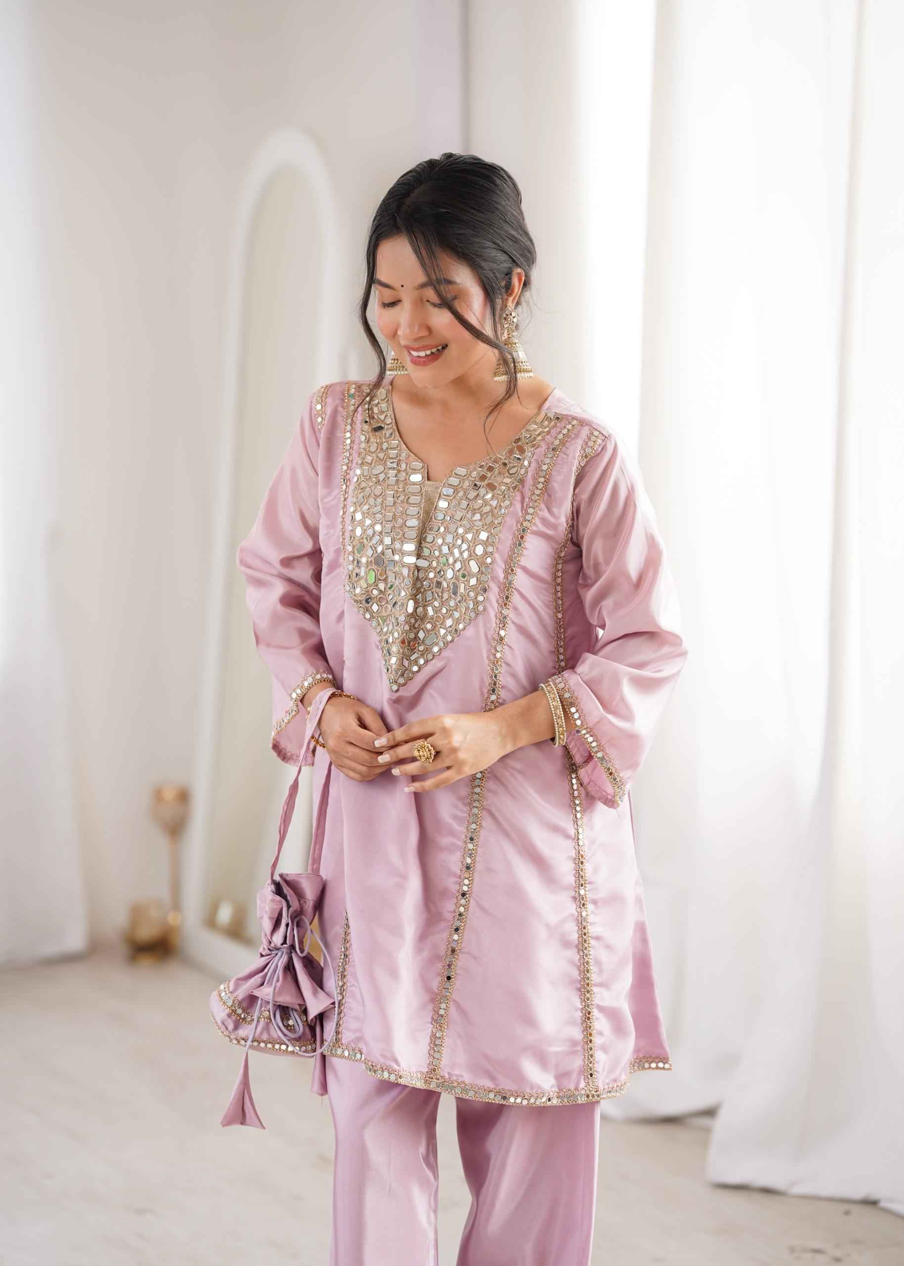 Front view of full three piece pink festive outfit showcasing a real mirror embroidered short kurti matching trousers and a batwa purse.