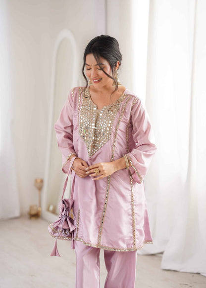 Front view of full three piece pink festive outfit showcasing a real mirror embroidered short kurti matching trousers and a batwa purse.