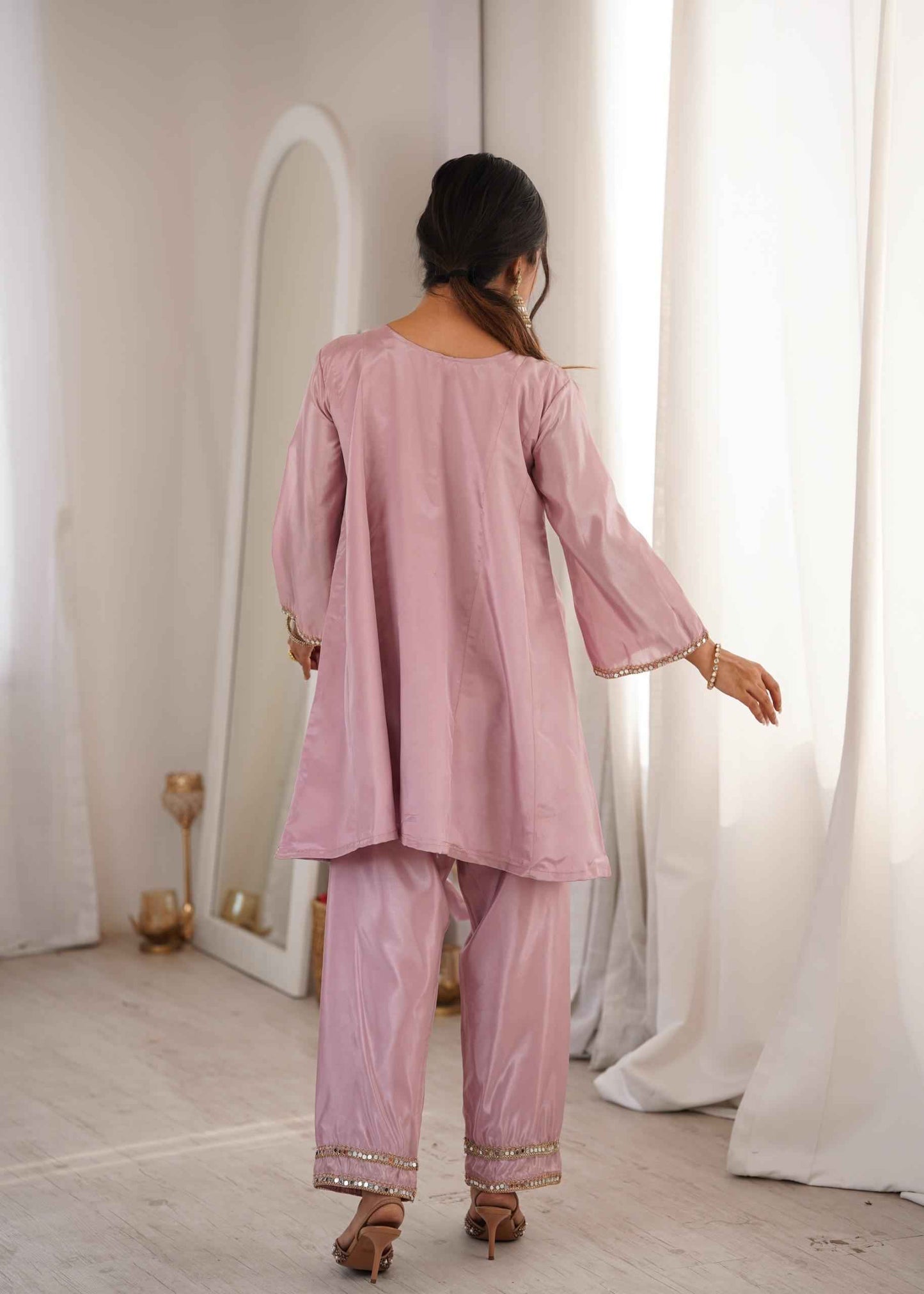 Side perspective of the stitched pink ethnic dress highlighting the elegant full length bell sleeves and standard tailoring.