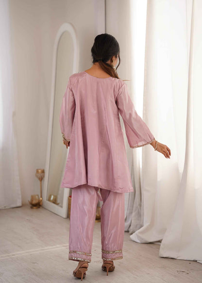 Side perspective of the stitched pink ethnic dress highlighting the elegant full length bell sleeves and standard tailoring.