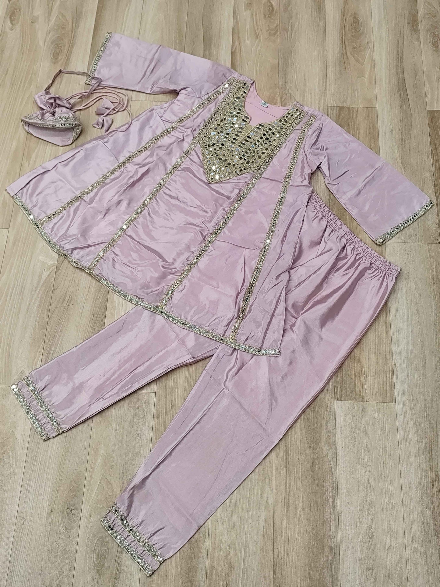 Close up view of authentic reflective real mirror work patterns and shimmering embroidered details on a soft pink neckline.