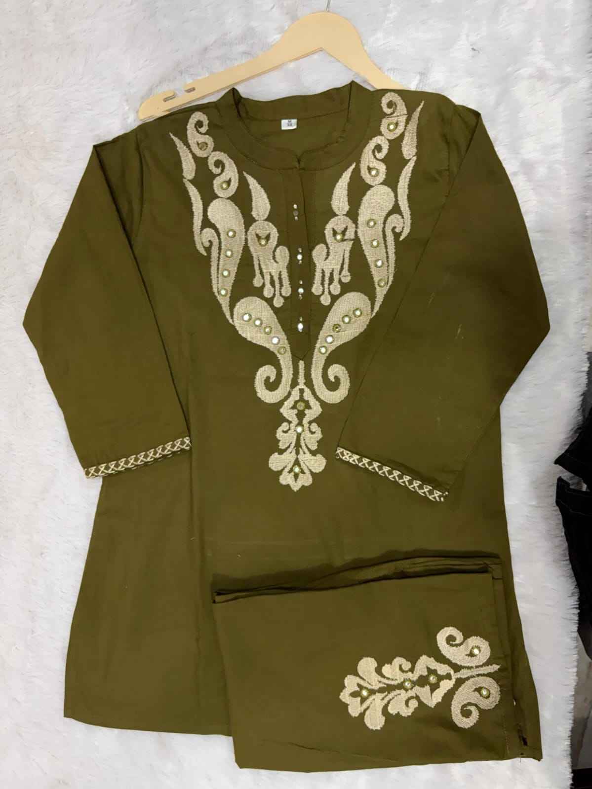  Close up view of detailed traditional full embroidery work and intricate needlework patterns on a premium olive green cotton sixty sixty fabric base.