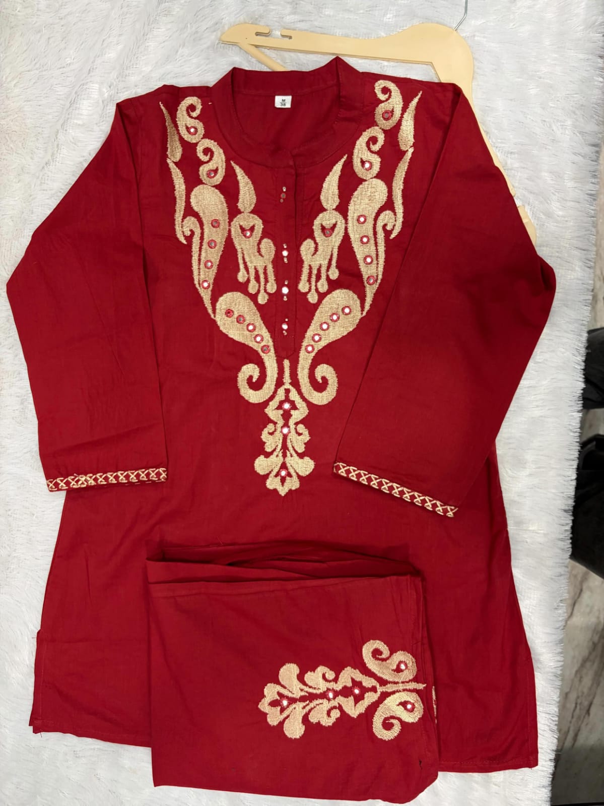 Close up view of detailed traditional full embroidery work and intricate needlework patterns on a premium maroon cotton sixty sixty fabric base.