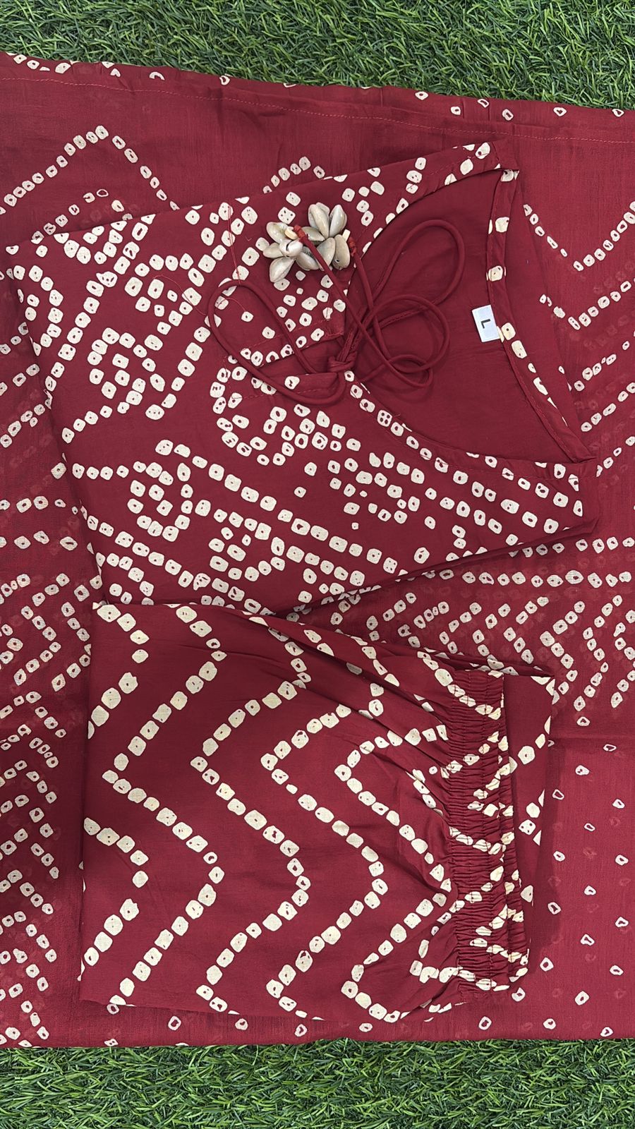 Close up view of traditional white bandhani discharge print dots and patterns on a rich deep wine cotton fabric base.