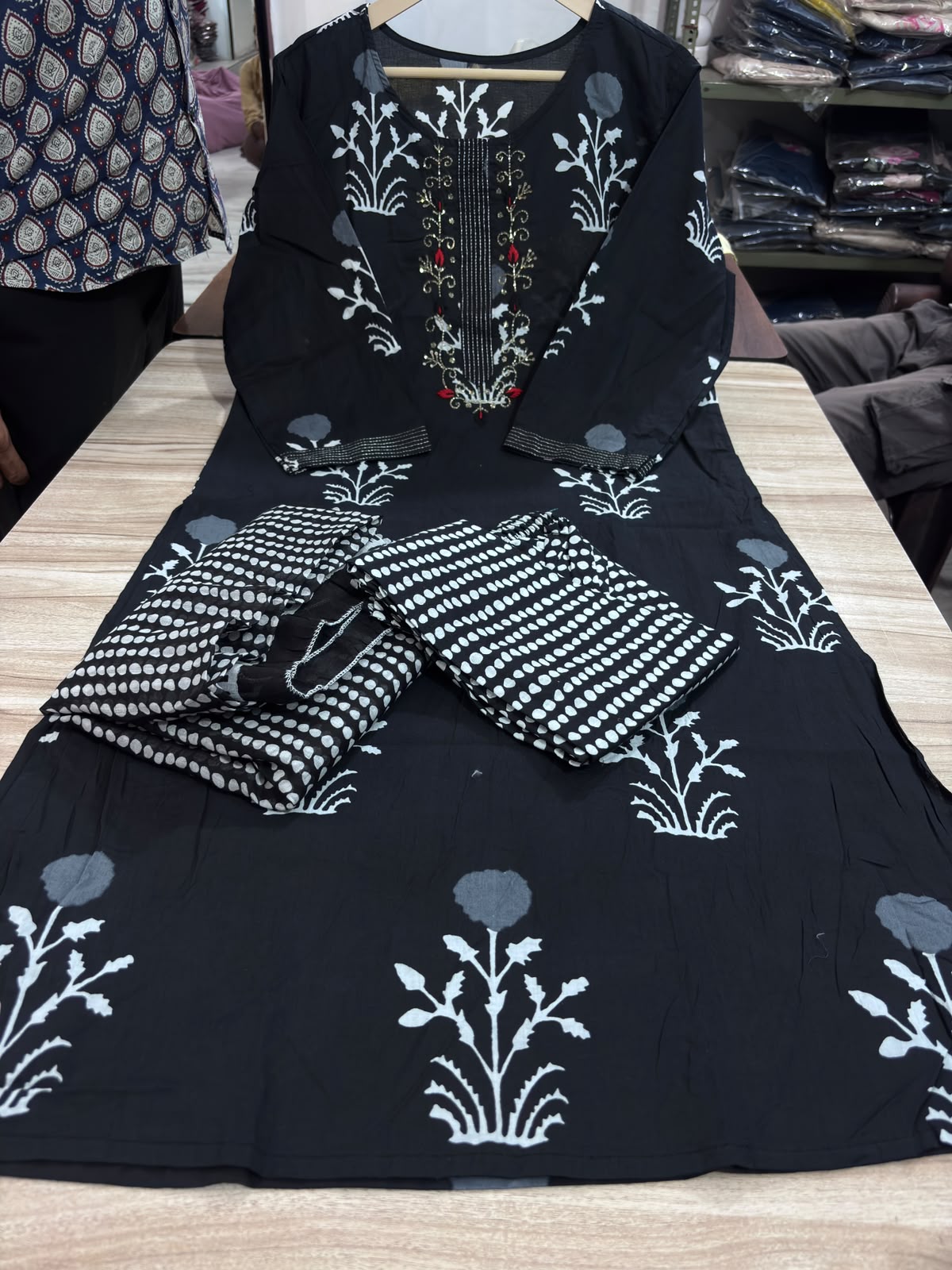 Close up view of detailed traditional artisan neck handwork embroidery patterns on a rich solid black cotton kurta bodice.