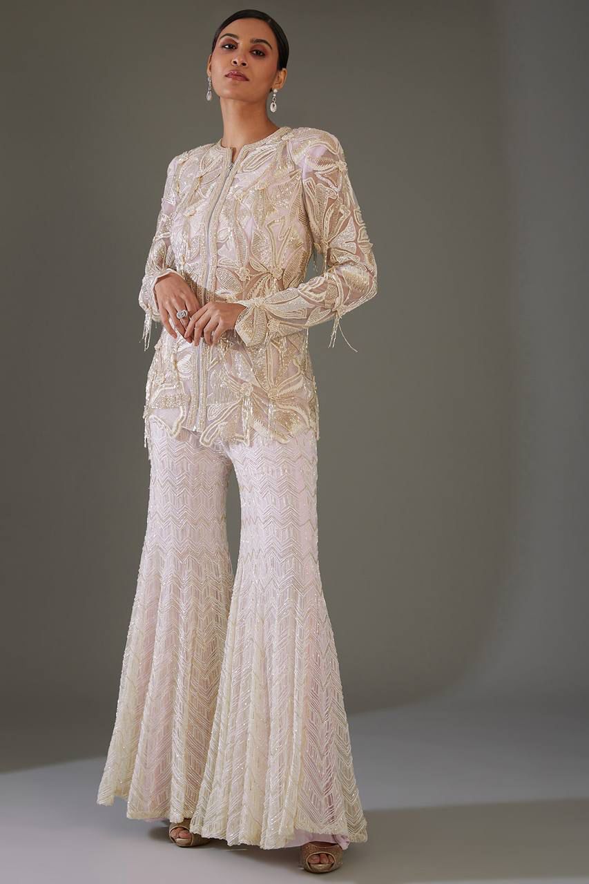 Front view of full two piece dusty rose traditional festive outfit displaying an embroidered georgette tunic top and matching sequence work palazzo trousers.