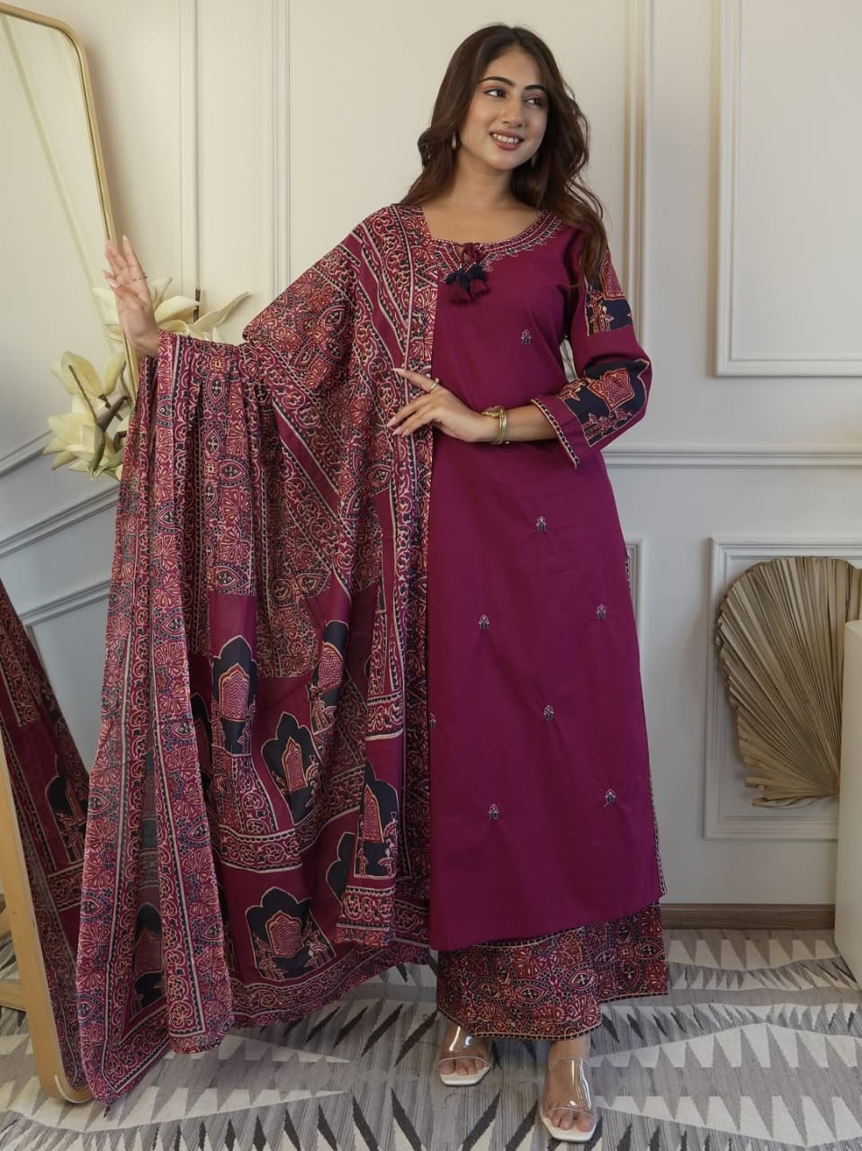 Front view of full three piece wine color heavy cotton embroidered kurta set displaying a neck worked tunic top trousers and a light cotton dupatta scarf.