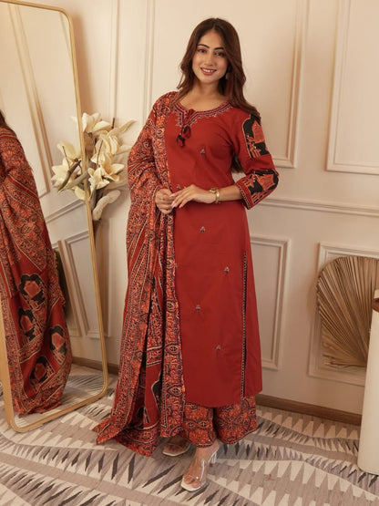 Front view of full three piece maroon heavy cotton embroidered kurta set displaying a neck worked tunic top trousers and a light cotton dupatta scarf.