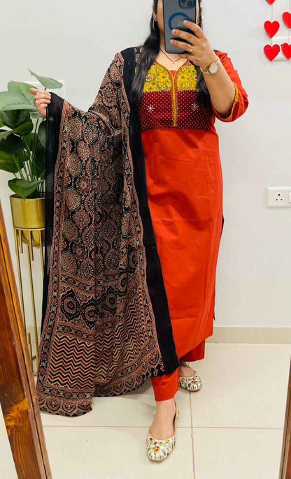 Front view of full three piece red cotton print hand work suit displaying a printed tunic top straight pants and a mulmul dupatta.
