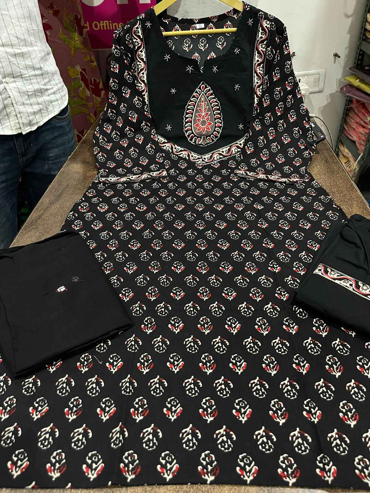 Close up view of detailed traditional hand work and premium intricate thread embroidery patterns on a rich solid black heavy cotton kurta bodice.