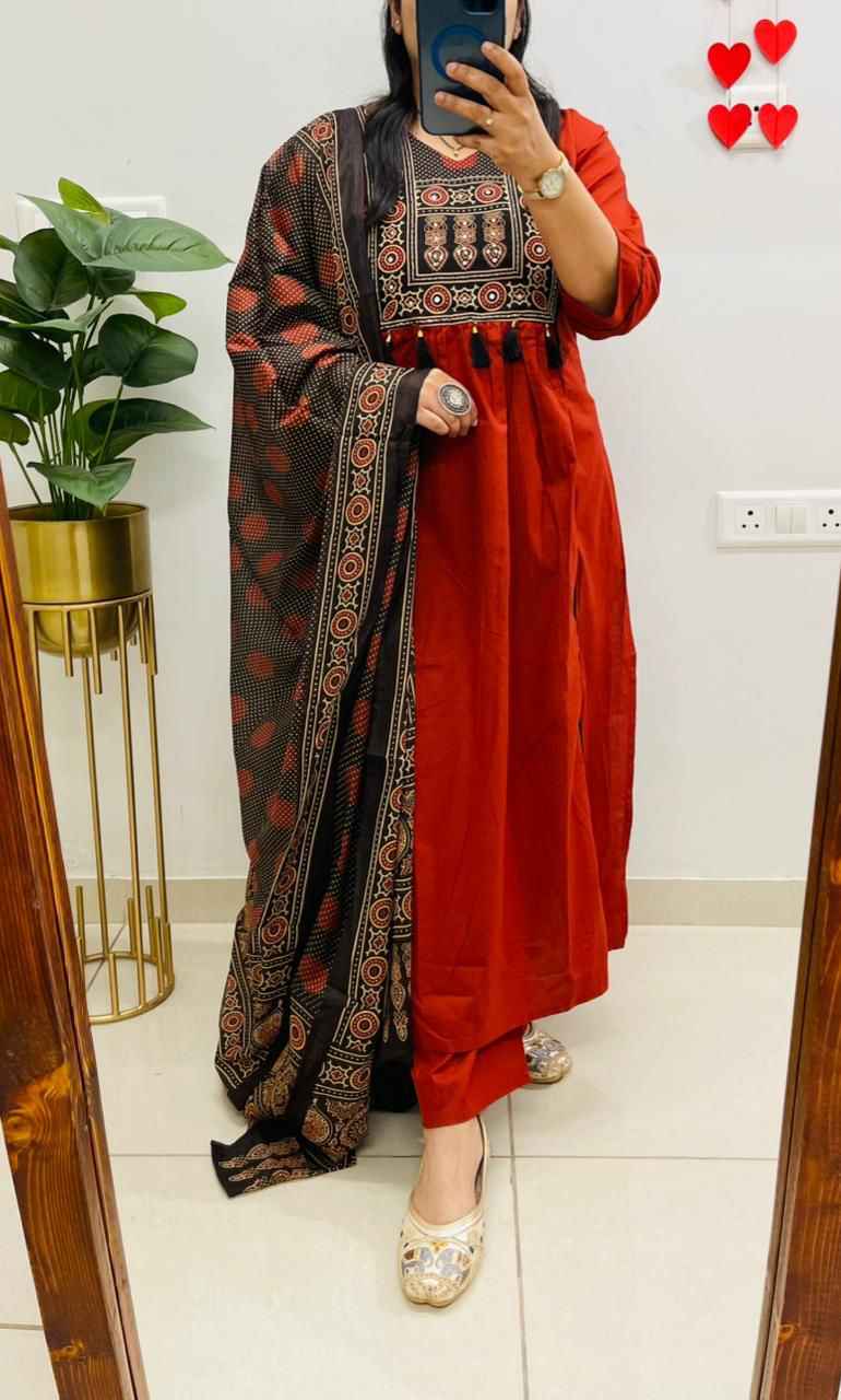 Front view of full three piece red heavy cotton hand work kurti set displaying a decorated straight tunic top matching pants and a light cotton dupatta scarf.