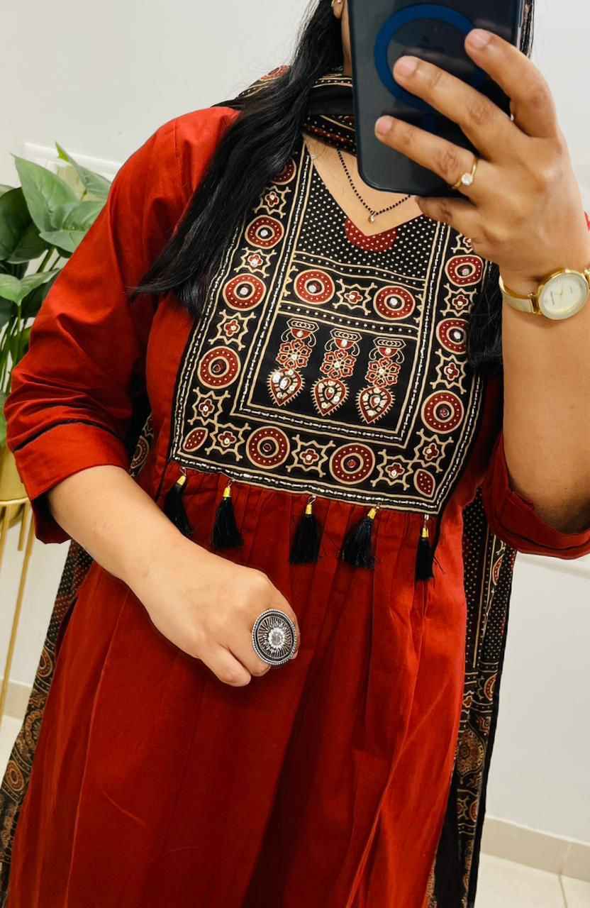 Close up view of detailed traditional hand work embroidery and premium hanging tassel accents on a rich red heavy cotton kurta bodice.