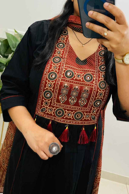 Close up view of detailed traditional hand work embroidery and premium hanging tassel accents on a sleek black heavy cotton kurta bodice.