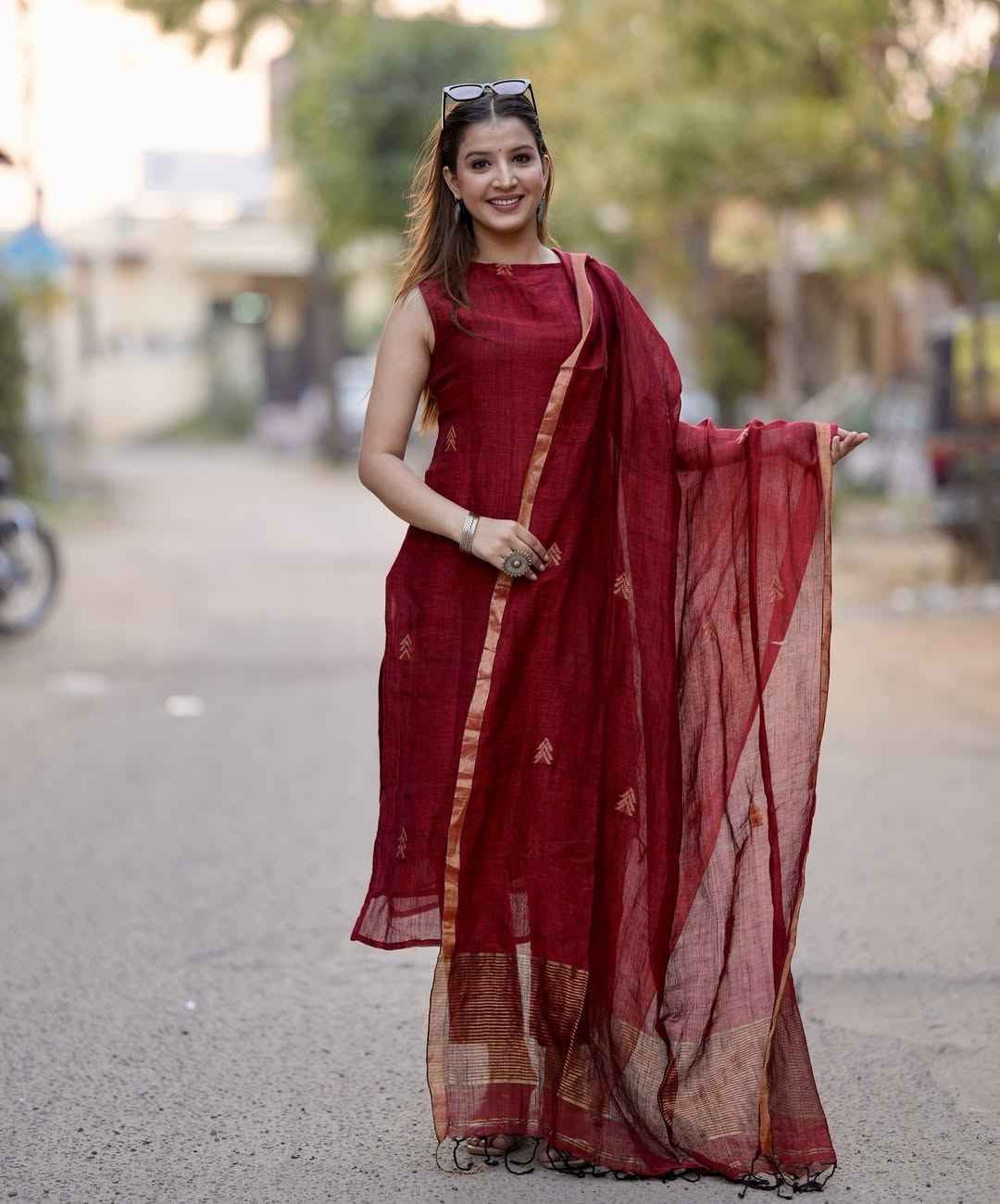 Front view of full three piece maroon sulabh cotton a line kurti set displaying a sleeveless halter neck tunic palazzo pants and weaved linen dupatta.