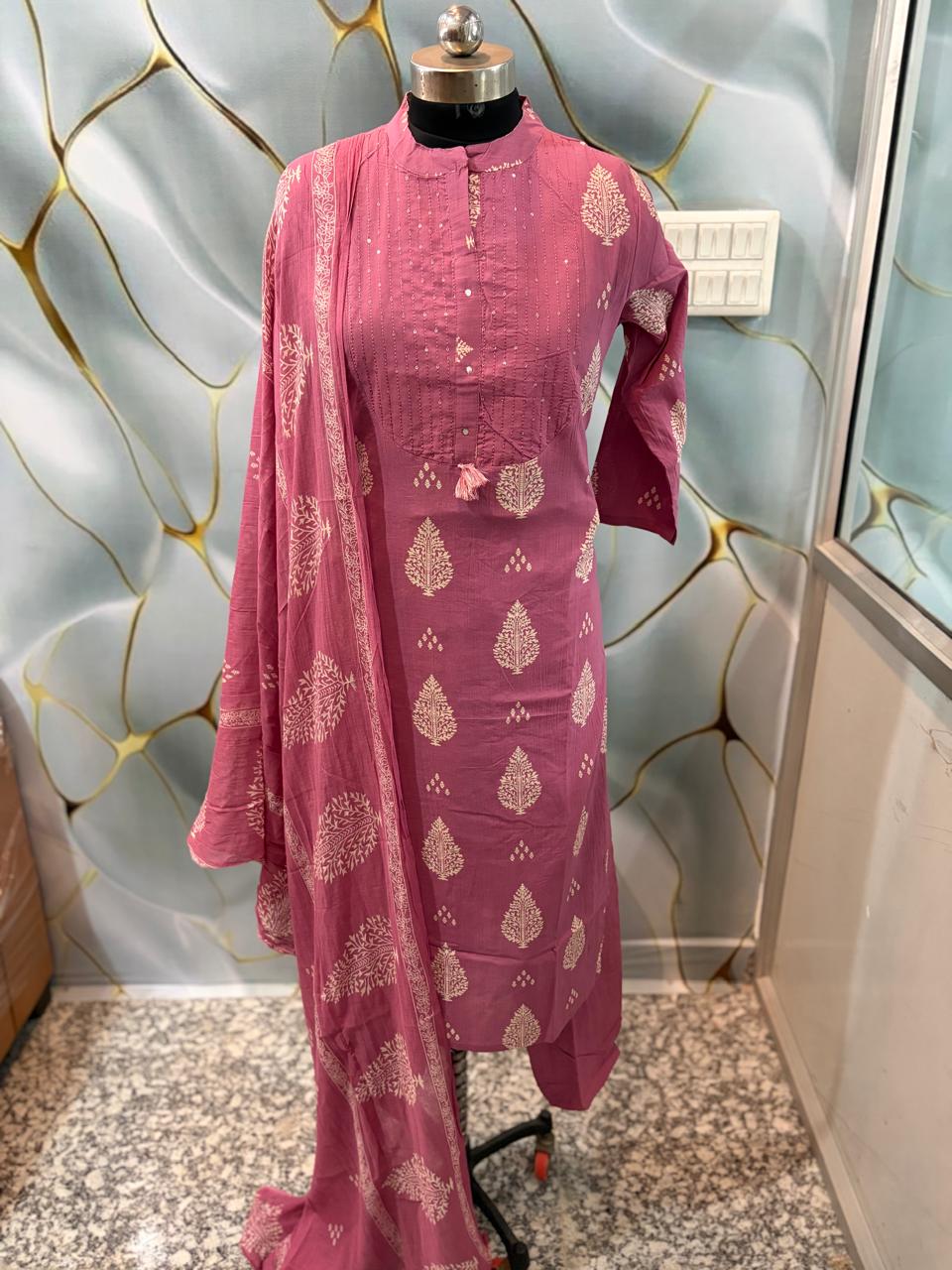 Close up view of detailed ethnic discharge print patterns and fine yoke highlighting lines on a soft onion pink cotton fabric bodice.