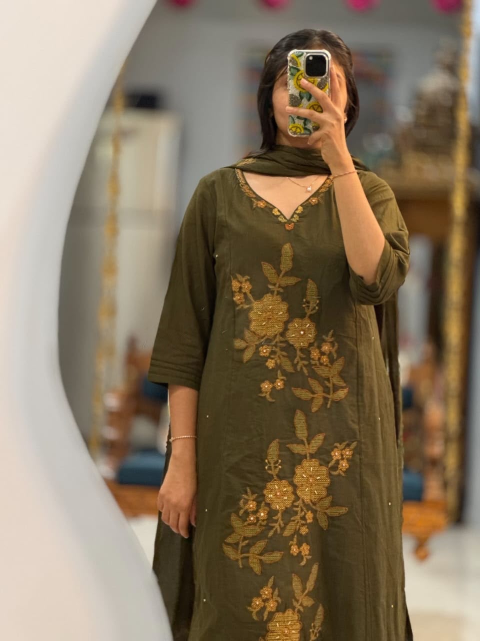 Close up view of detailed traditional print motifs and premium heavy yoke embroidery work on a deep olive green cotton fabric bodice.