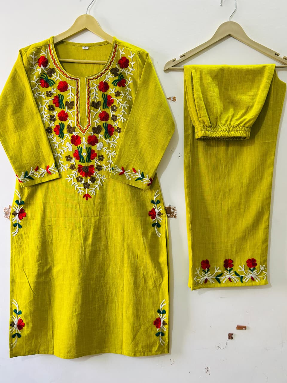 Close up view of detailed manual artisan heavy aari work embroidery and intricate thread design patterns on a lemon green cotton fabric bodice.