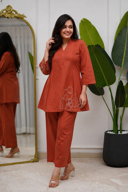 Front view of full two piece rust orange premium cotton embroidered palazzo set displaying a beautifully embroidered tunic top and matching wide leg trousers.