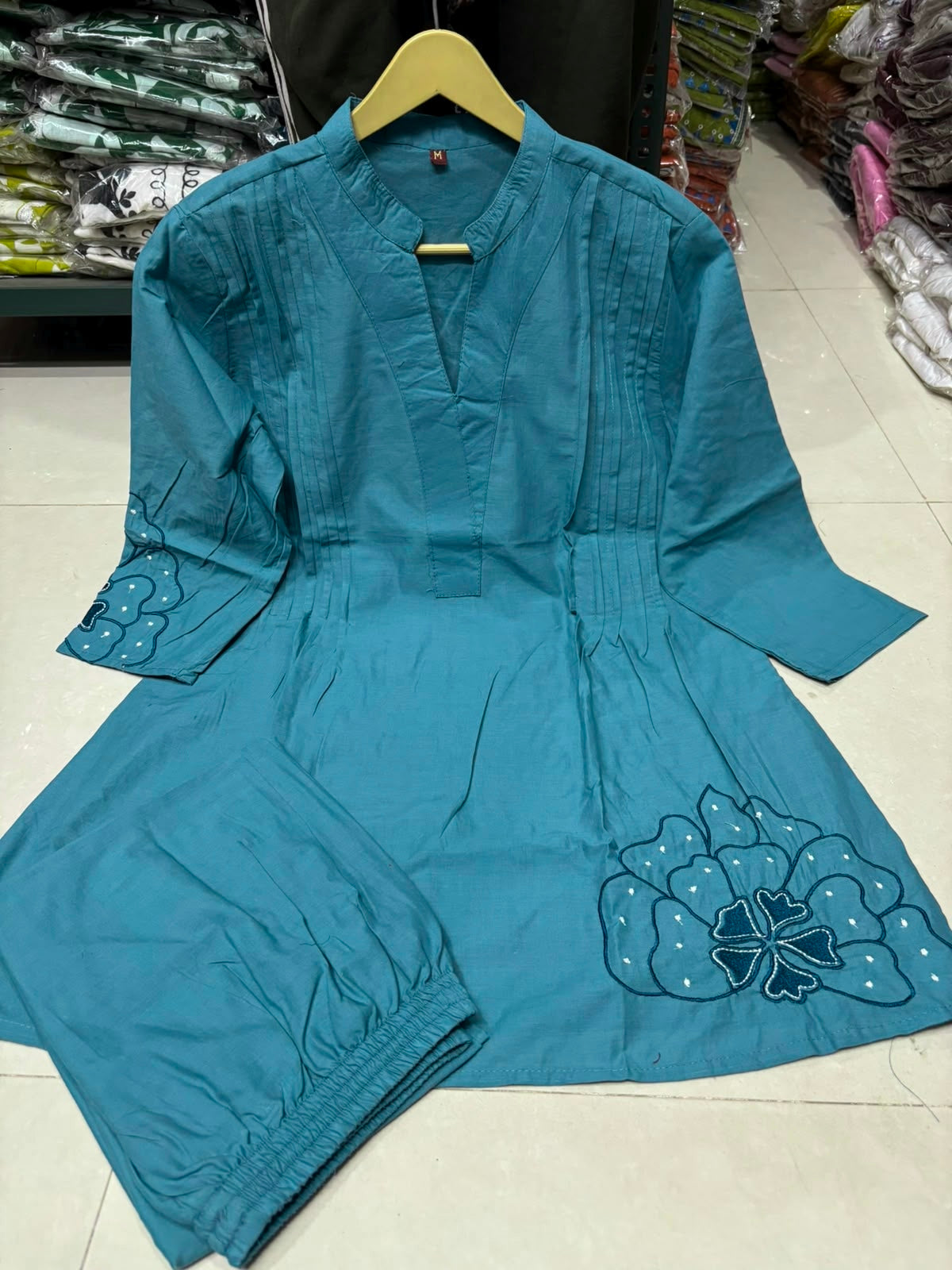 Close up view of detailed traditional embroidery work and high quality thread work patterns on a rich tea blue cotton fabric bodice canvas.
