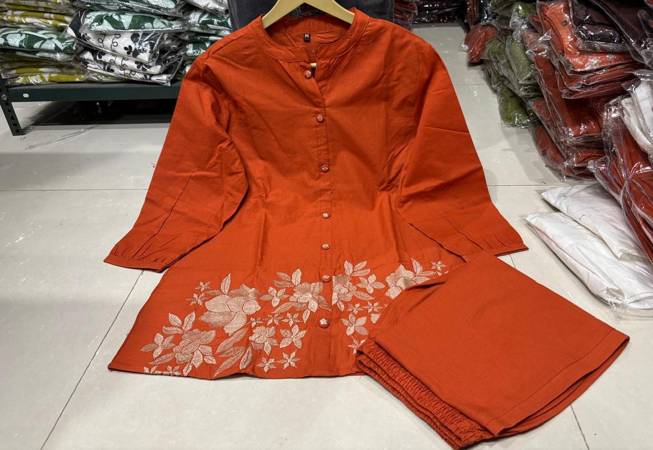 Close up view of detailed traditional embroidery work and high quality thread work patterns on a rich rust orange cotton fabric bodice canvas.