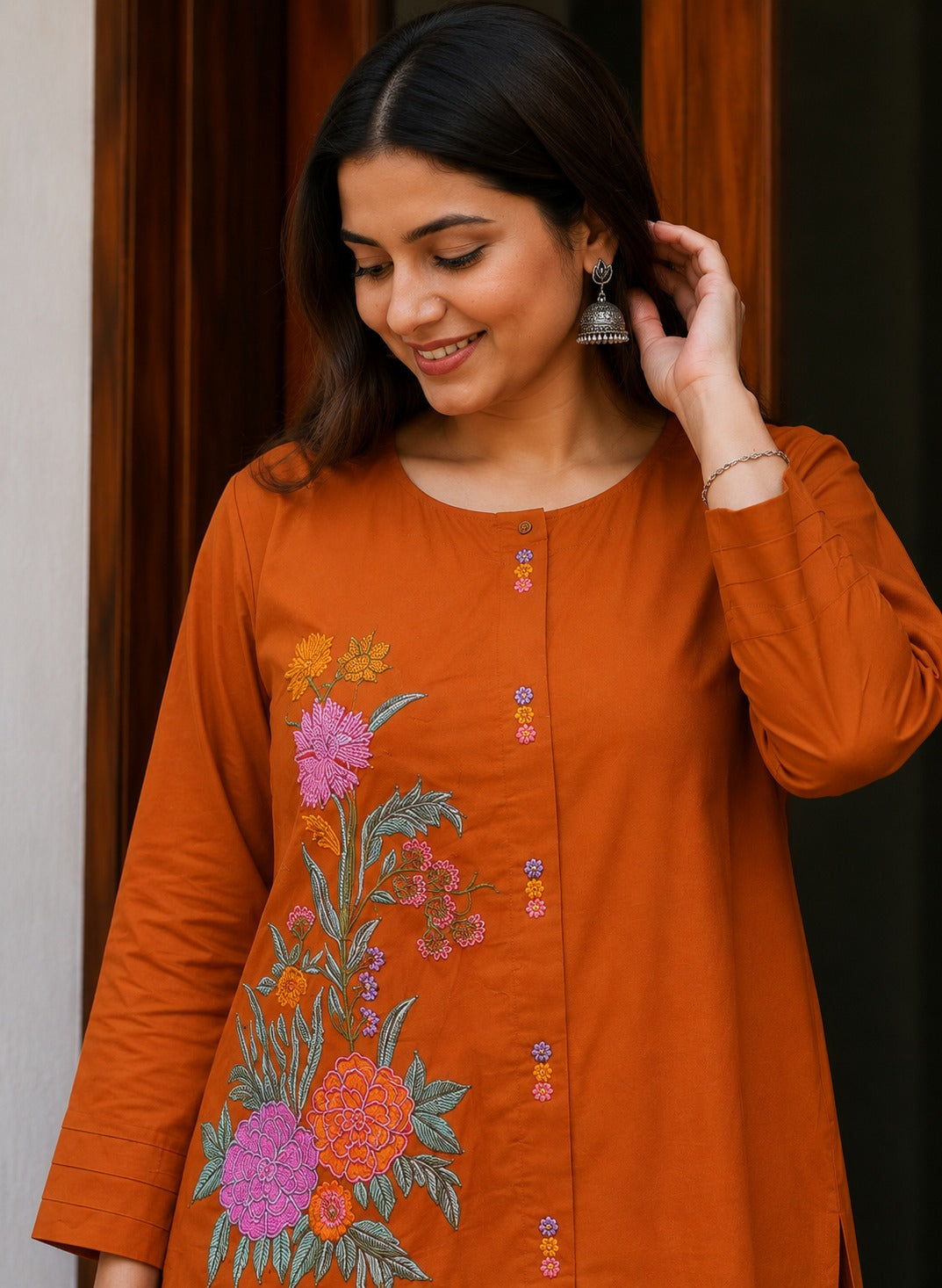 Close up view of detailed traditional embroidery work and high quality thread work patterns on a rich rust orange cotton fabric bodice canvas.