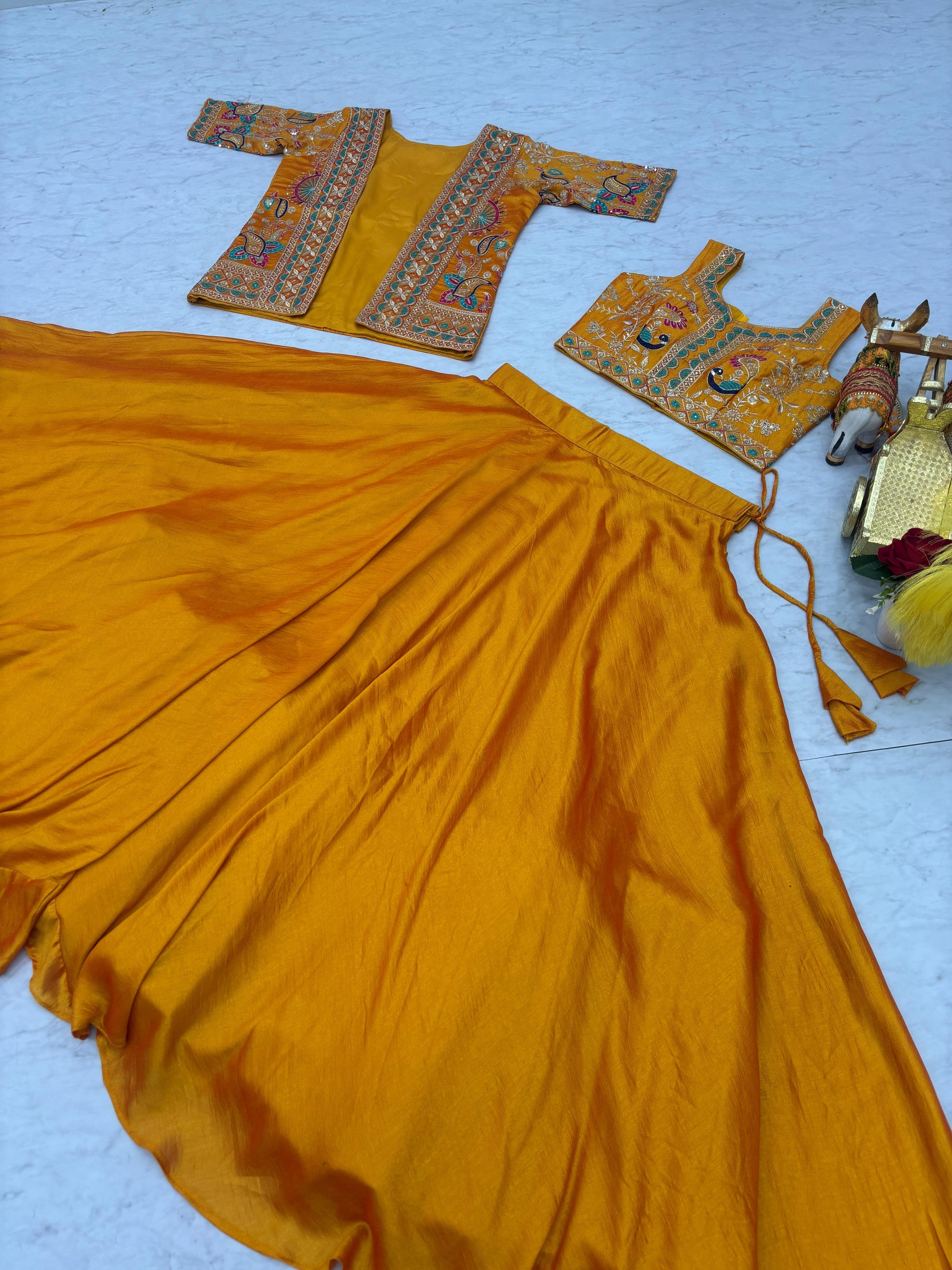 Close up details of intricate thread embroidery patterns on premium smooth mustard yellow silk fabric.