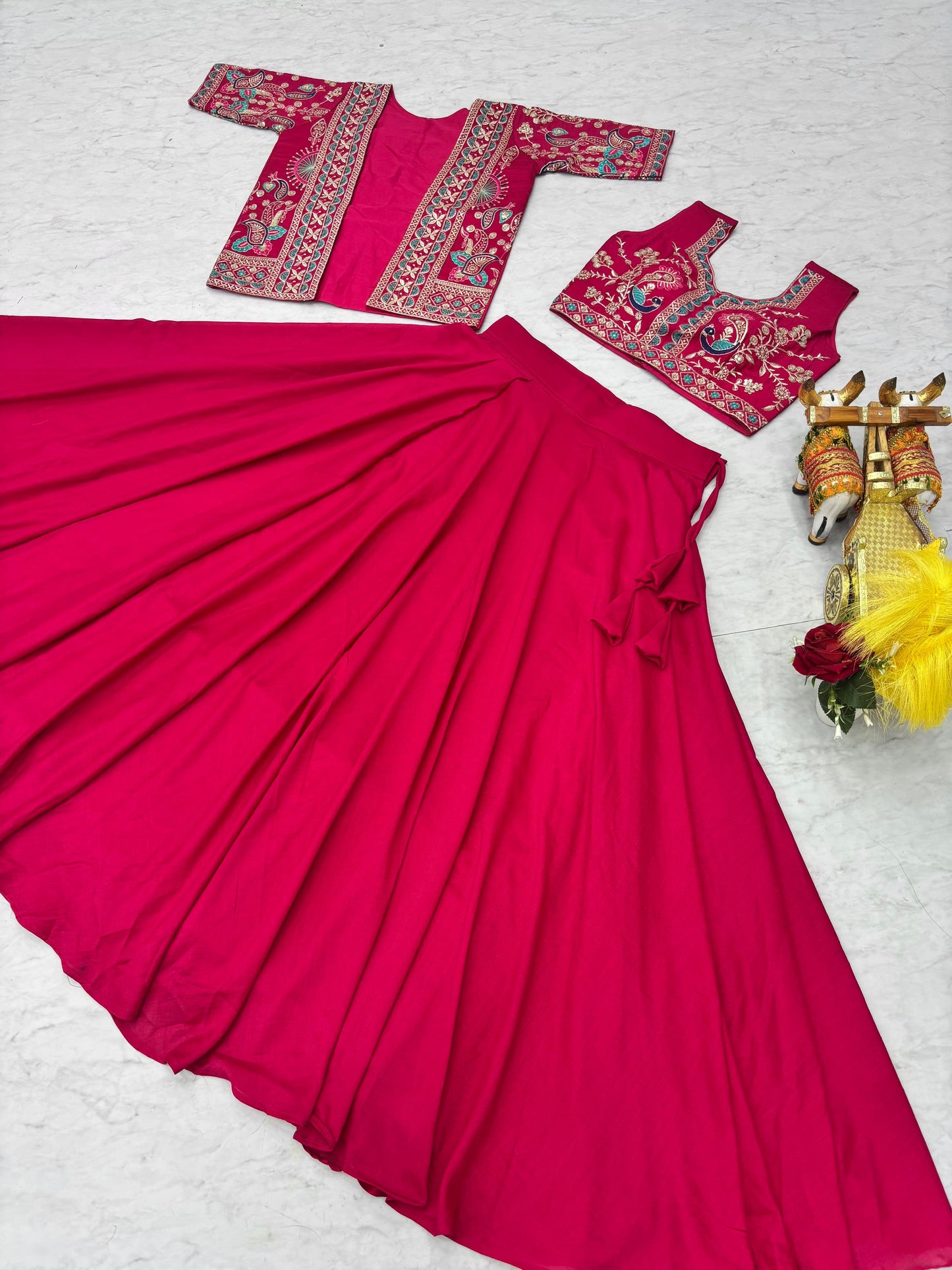Detailed close view of colorful heavy thread embroidery work on a bright rani pink traditional top.