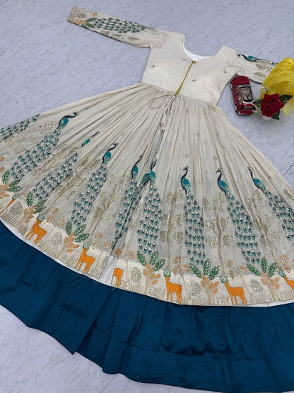 Close up view of detailed metallic thread needlework and shimmering sequence embroidery patterns on deep peacock blue silk fabric.