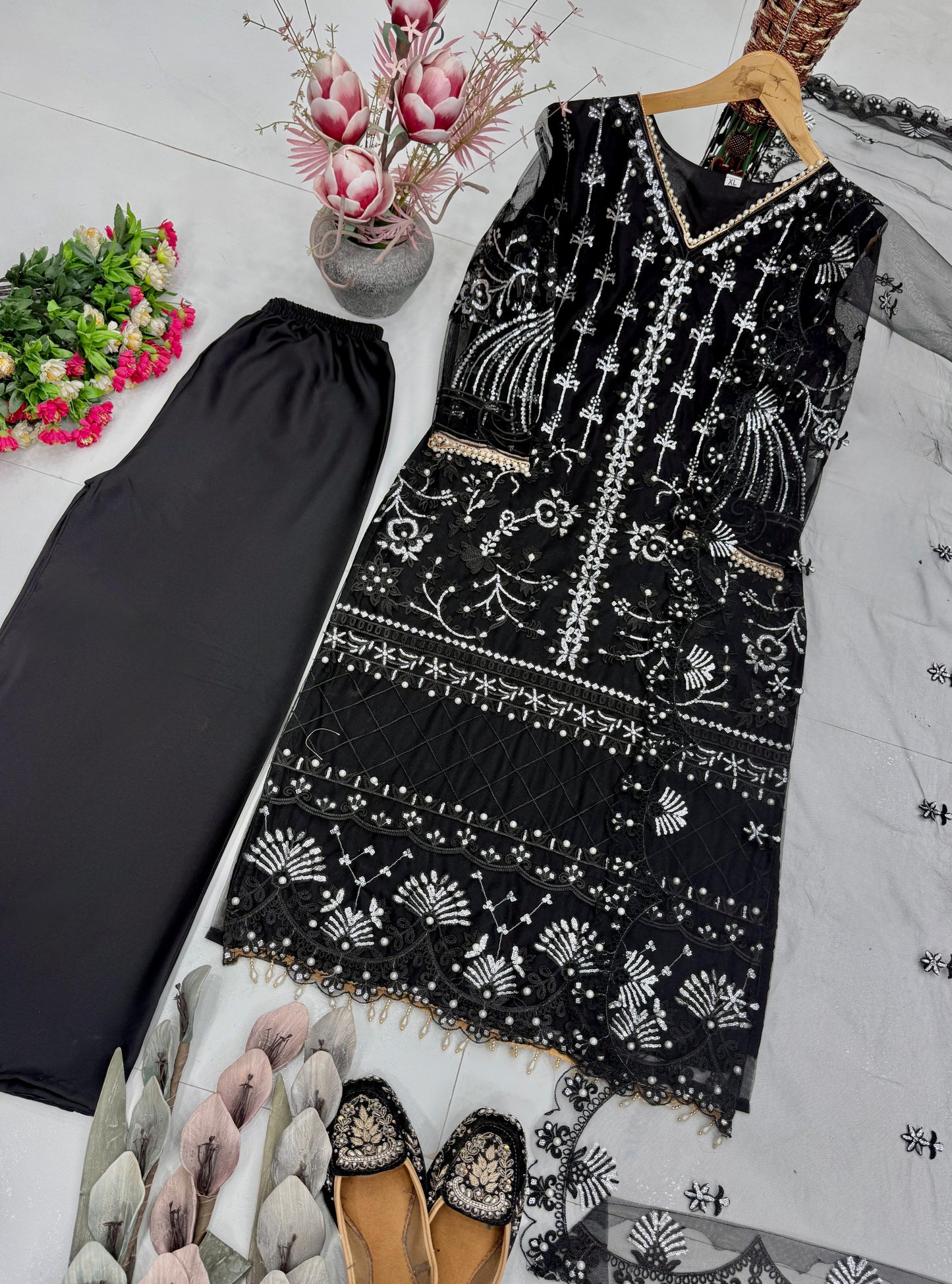 Focused shot of beautiful artisan pearl hand work and glossy chine sequence textures on deep black net fabric near the neckline.
