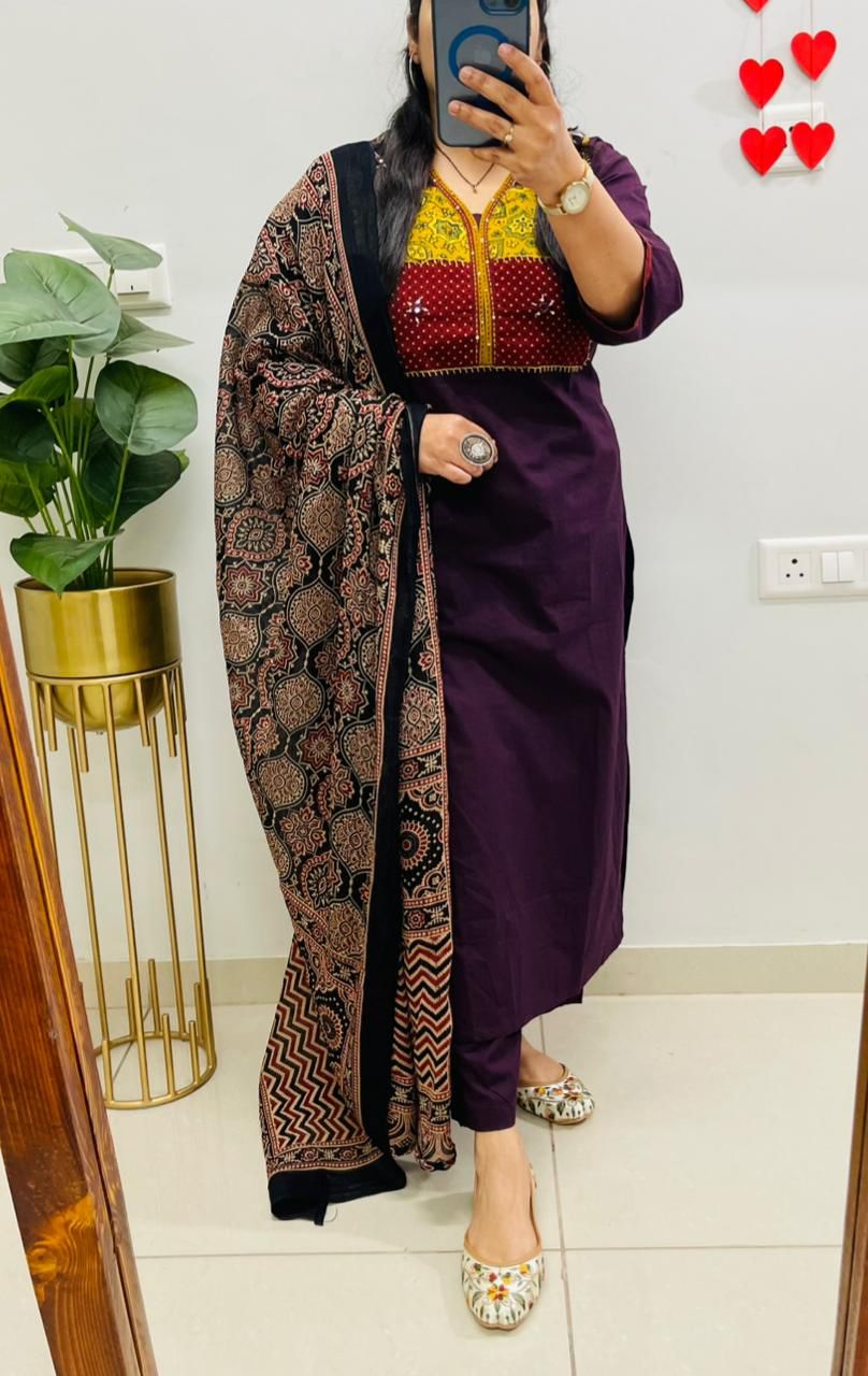 Front view of full three piece wine color cotton print hand work suit displaying a printed tunic top straight pants and a mulmul dupatta.