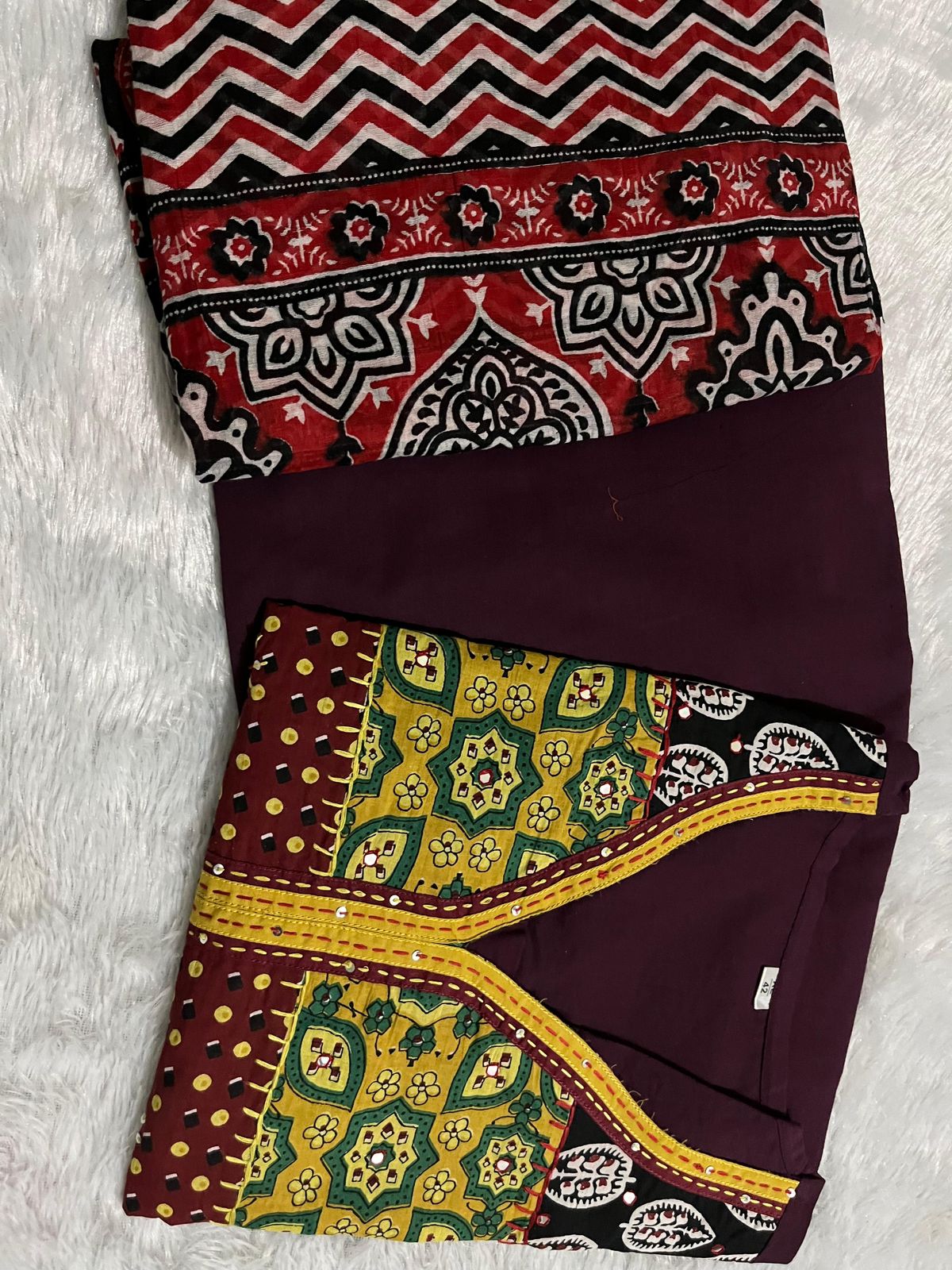 Side perspective presentation of the fully stitched wine color ethnic tunic highlighting the clean tailored borders and regular forty six plus inch length outline.