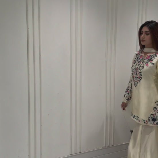 High definition retail display video highlighting the premium quality shine of the embroidery work and the smooth movement of the off white crape silk fabric under warm studio lights.